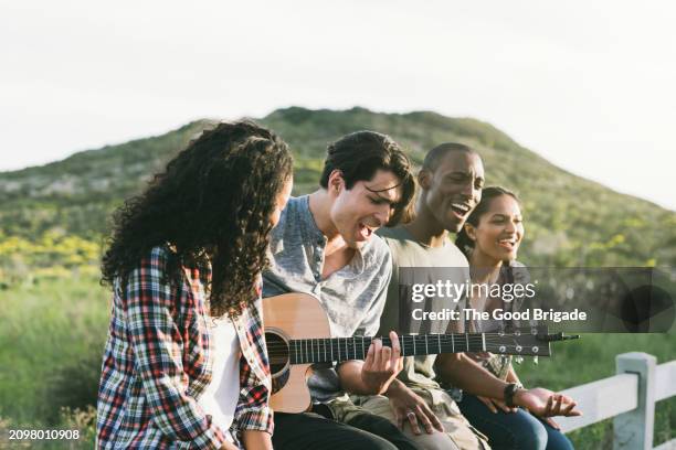 young friends playing guitar and singing together against sky - malibu nature stock pictures, royalty-free photos & images