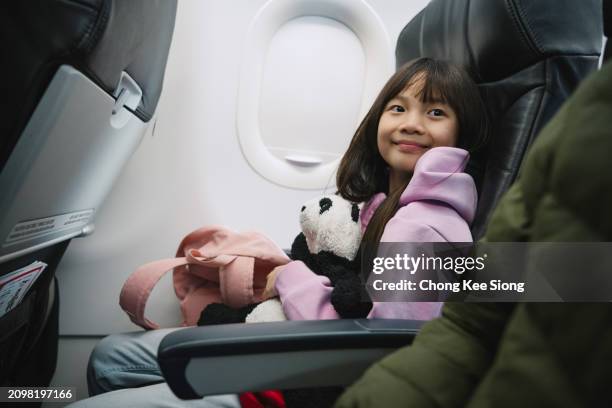 cute little girl travelling by plane - vliegtuigstoel stockfoto's en -beelden