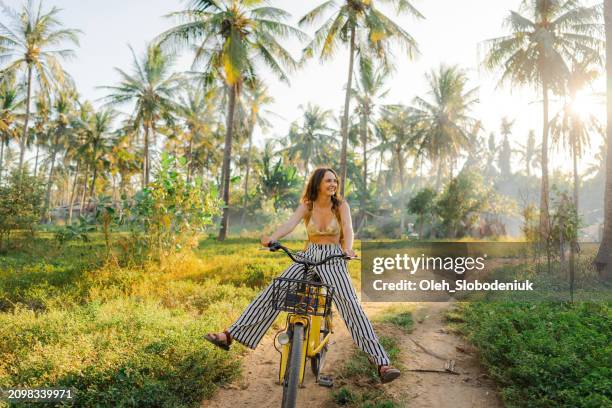 mujer alegre que anda en bicicleta a través del cocotero en gili trawangan - coco fruta tropical fotografías e imágenes de stock