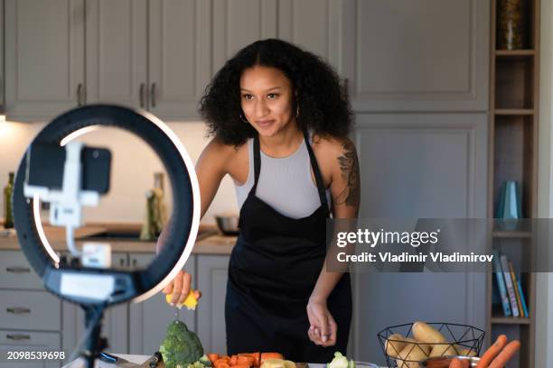 a woman cooking and live streaming a video - influencer stock pictures, royalty-free photos & images