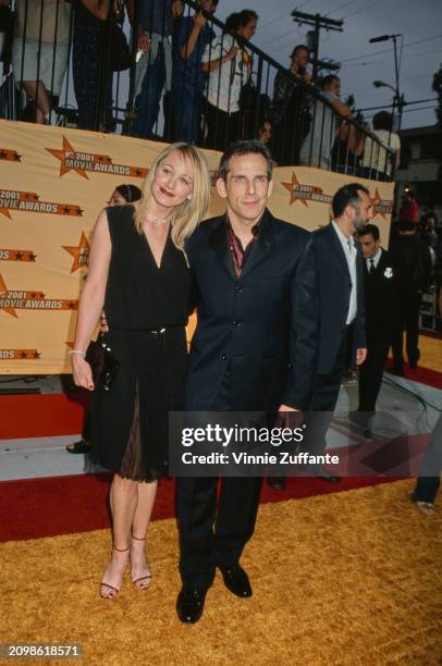 American actress Christine Taylor, wearing a sleeveless black v-neck dress, and her husband, American actor and comedian Ben Stiller, who wears a...