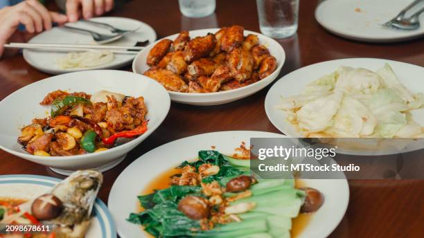 closeup of young asian family eating food and having fun sitting at dining table at backyard outside home. multi-generation family enjoying spending together. - chinese eating backyard stock pictures, royalty-free photos & images