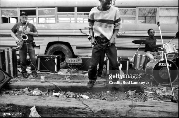 View of the members of an unidentified Blues band perform, in front of an abandoned school bus, at the Maxwell Street Flea Market in the Southside...