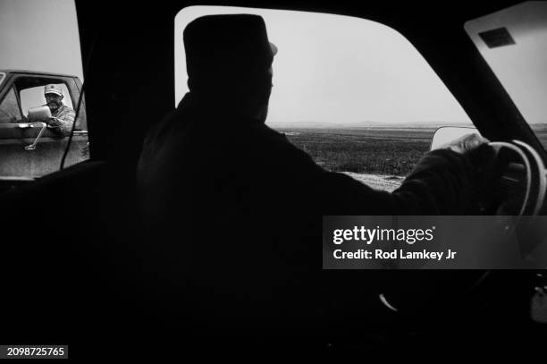 Silhouette of farmer Lester Vincent as he talks, through the window of his truck, to an unidentified man following flooding in the area, Hull,...