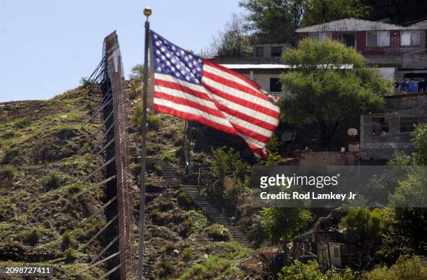 View of an American flag above the border wall between the United States & Mexico, Nogales, Arizona, July 25, 2002.