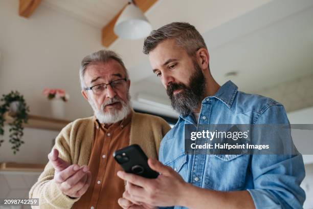 elderly man struggles with technology, mobile apps, smartphone not working. - diferença entre gerações - fotografias e filmes do acervo