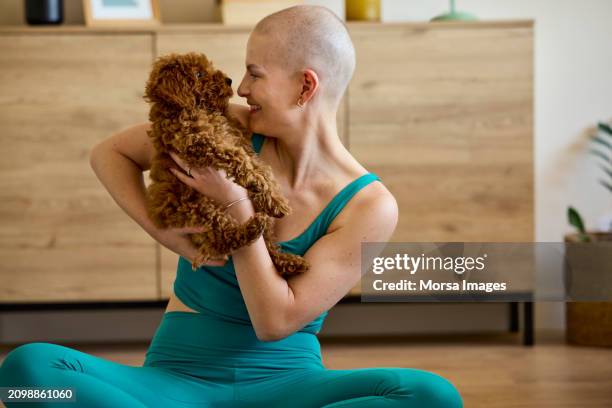 happy active female cancer patient playing with dog at home - cellule cancéreuse photos et images de collection