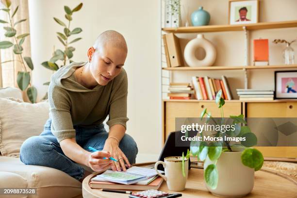 female freelancer writing in diary at home - cellule cancéreuse photos et images de collection