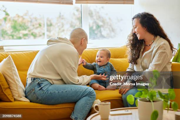 best friend visiting cancer patient. friends playing with cheerful toddler on sofa - alopecia fotografías e imágenes de stock