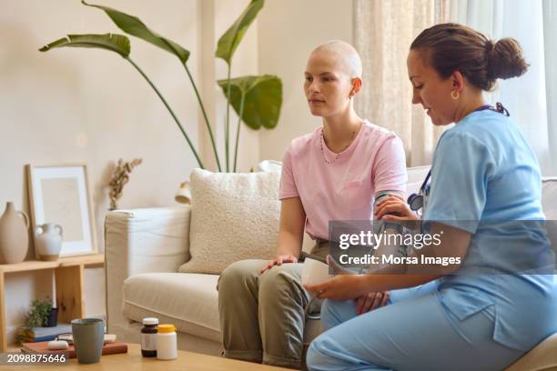 nurse checking blood pressure of a female cancer patient at home - cancer cell stock pictures, royalty-free photos & images