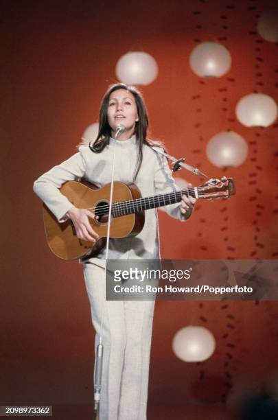 American singer Julie Felix performs playing an acoustic guitar on the set of a music television show in London circa 1970.
