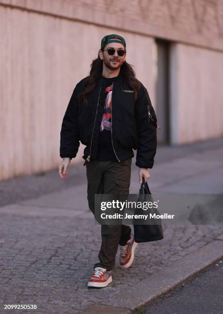 Riccardo Simonetti seen wearing Gucci gold / black sunglasses, Stetson green logo cap, Alpha Industries black oversized bomber jacket, black with...