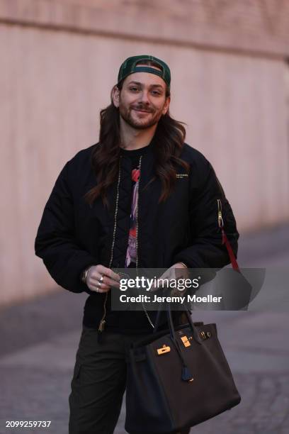 Riccardo Simonetti seen wearing Gucci gold / black sunglasses, Stetson green logo cap, Alpha Industries black oversized bomber jacket, black with...