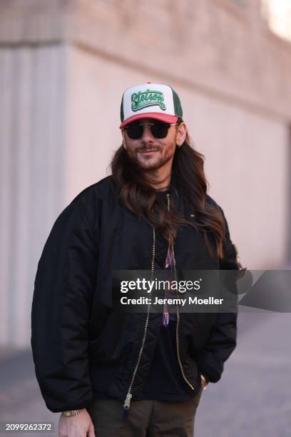 Riccardo Simonetti seen wearing Gucci gold / black sunglasses, Stetson green logo cap, Alpha Industries black oversized bomber jacket, black with...