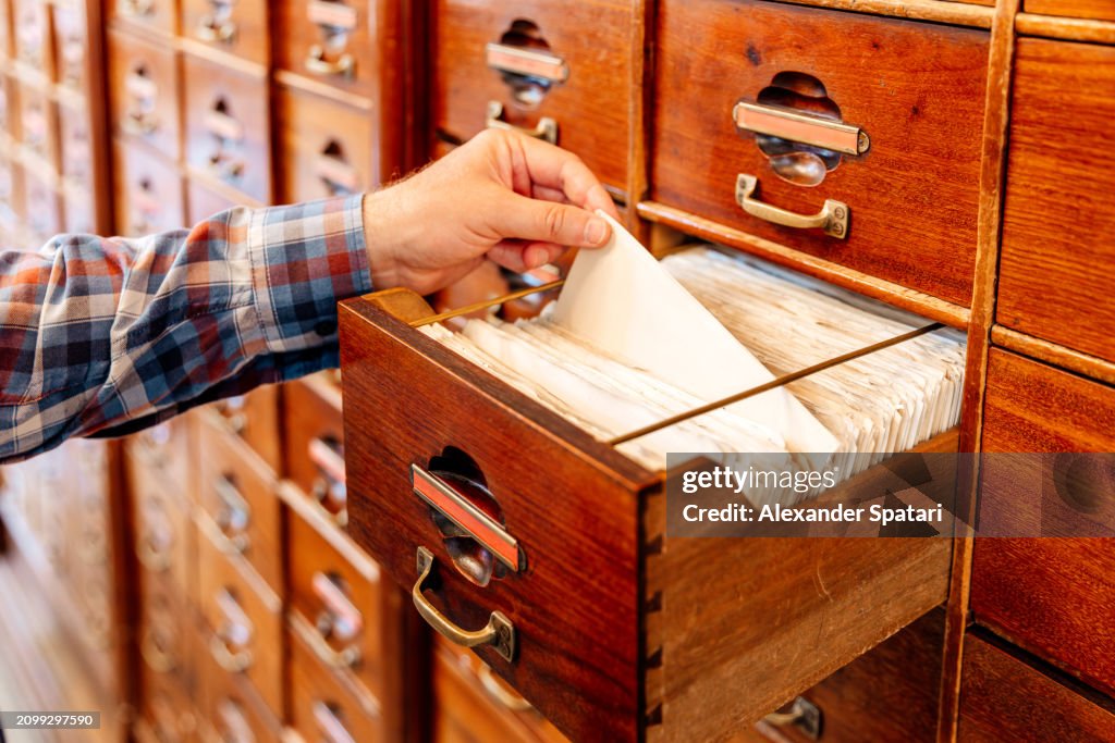 Person flipping through files of indexed cards at the library