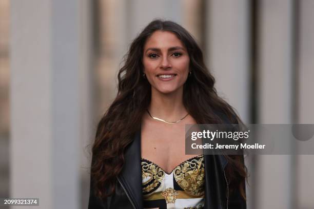 Michelle Golke seen wearing gold necklace, black / white / yellow pattern crop top and black leather biker jacket, on March 19, 2024 in Berlin,...