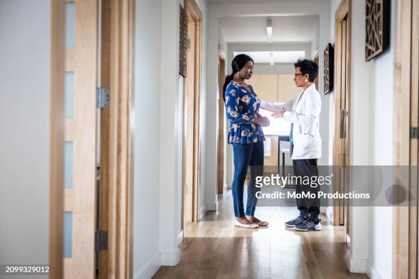 female doctor and patient having discussion in medical office hallway - daily life in multicultural birmingham stock pictures, royalty-free photos & images
