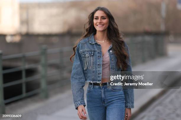 Michelle Golke seen wearing gold necklace, light pink lace crop top, blue denim cropped denim jacket, matching blue denim wide leg pants / jeans,...