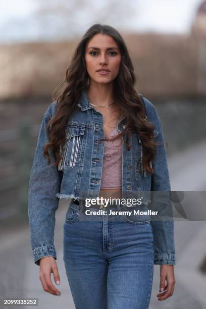 Michelle Golke seen wearing gold necklace, light pink lace crop top, blue denim cropped denim jacket, matching blue denim wide leg pants / jeans,...