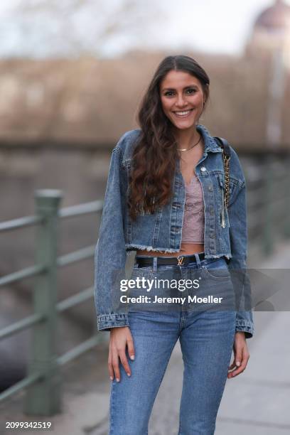 Michelle Golke seen wearing gold necklace, light pink lace crop top, blue denim cropped denim jacket, matching blue denim wide leg pants / jeans,...