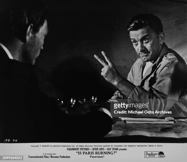 French actor Pierre Vaneck and American actor and film director Kirk Douglas, who gestures with two fingers, in a scene from 'Is Paris Burning?',...