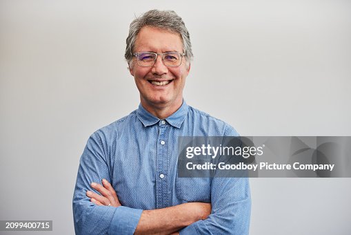 Mature businessman smiling with his arms crossed against a blue wall Mature businessman smiling with his arms crossed against a blue wall
