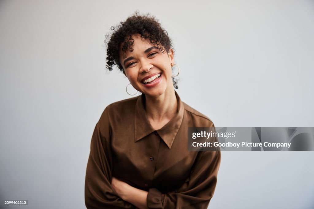 Laughing young businesswoman standing in front of an office wall