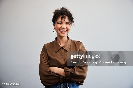 Laughing yougn businesswoman standing with her arms crossed against an office wall Laughing yougn businesswoman standing with her arms crossed against an office wall