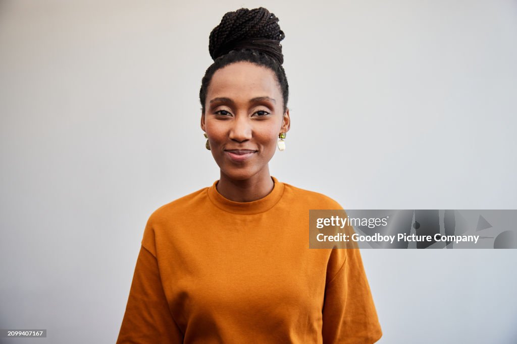 Confident young businesswoman standing in front of a white office wall