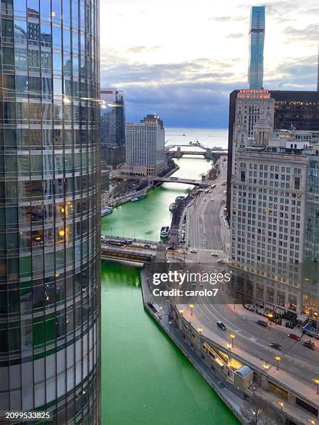 chicago river dyed green for st. patrick's day, runs under bridges and out to lake michigan. - st patricks day stock pictures, royalty-free photos & images