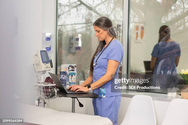 médica atualiza prontuários de pacientes em laptop - registo-médico-eletrónico - fotografias e filmes do acervo