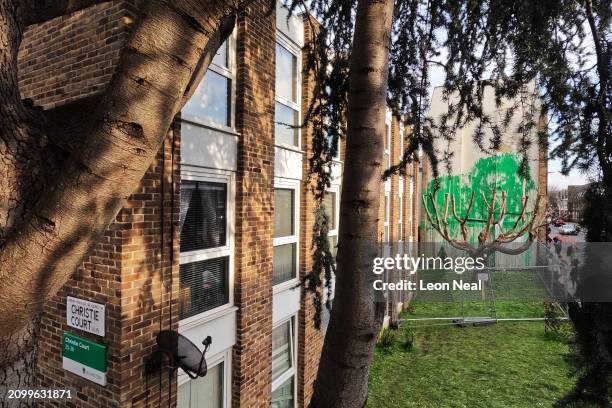 Mural by the artist Banksy is seen in the distance following it's defacement with white paint, on March 20, 2024 in the Finsbury Park area of London,...