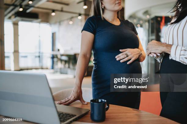 pregnant businesswoman talking to coworker - zwanger stockfoto's en -beelden