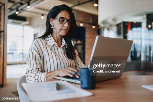 portrait of a businesswoman working on laptop - alleen oudere vrouwen stockfoto's en -beelden