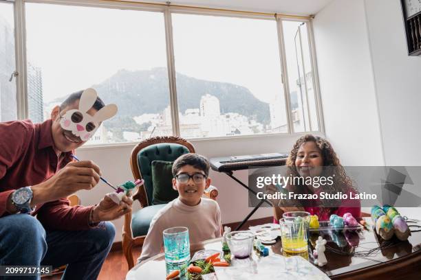 retrato de padres e hijo preparando la decoración para las vacaciones de pascua juntos en casa - easter bunny mask fotografías e imágenes de stock