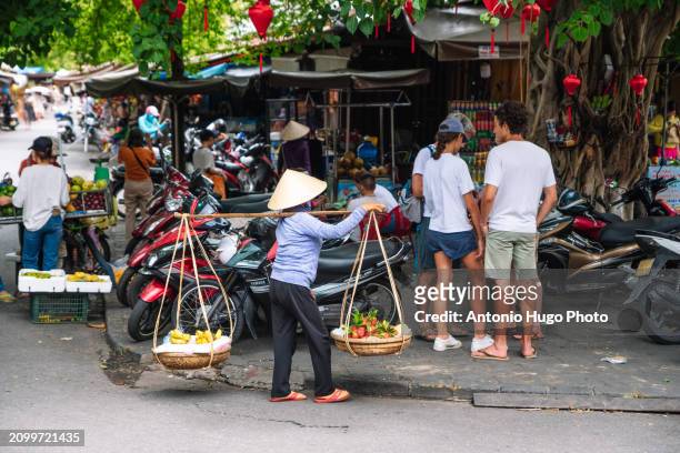vietnamese woman carrying fruit in the street - hanoi cityscape stock pictures, royalty-free photos & images