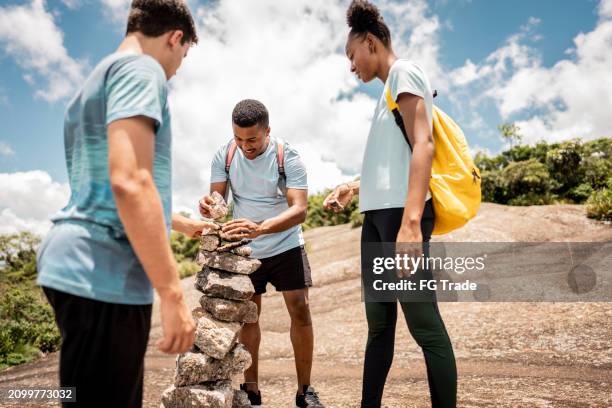 friends stacking stones on a mountain - gestapelde stenen stockfoto's en -beelden