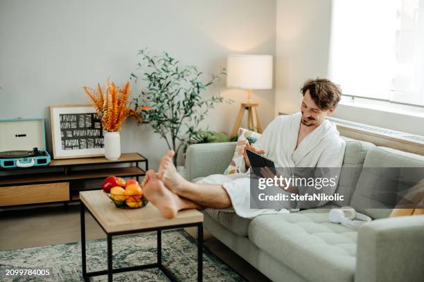 l'uomo usa una tavoletta digitale a casa - accappatoio foto e immagini stock