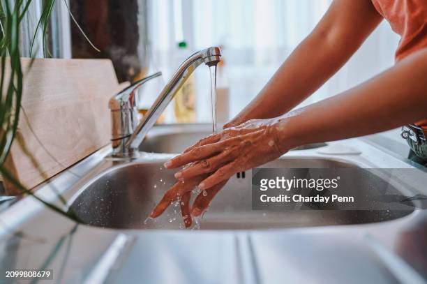 nahaufnahme einer frau, die sich unter fließendem wasser in der küchenspüle die hände wäscht - wasser ressource stock-fotos und bilder