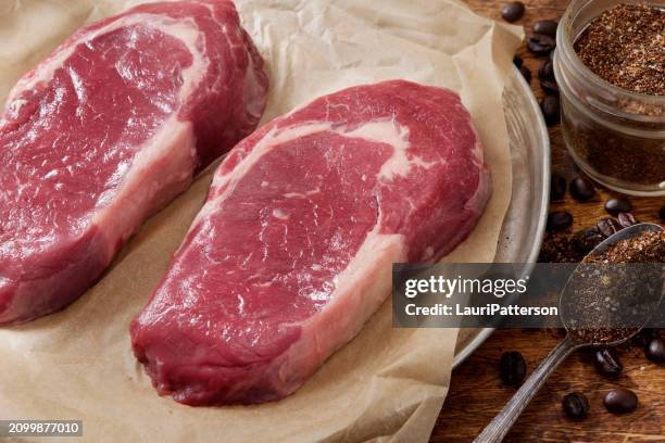 préparation de steaks de faux-filet désossés frottés à sec au café - bovin photos et images de collection