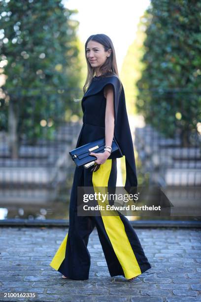 Guest wears a black top, wide-leg black and yellow pants, a black bag with gold details, outside Stella McCartney , during the Womenswear Fall/Winter...