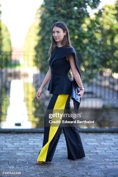 Guest wears a black top, wide-leg black and yellow pants, a black bag with gold details, outside Stella McCartney , during the Womenswear Fall/Winter...