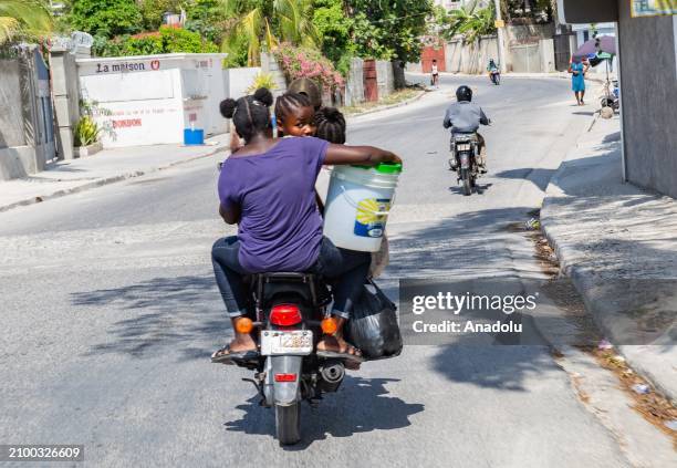 People pass by with a 15-liter plastic bucket on a motorcycle, against the backdrop of continuing insecurity and political instability in...