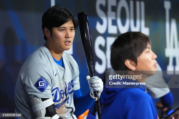 Shohei Ohtani of the Los Angeles Dodgers talks to his interpreter Ippei Mizuhara in the dugout during the 2024 Seoul Series game between Los Angeles...