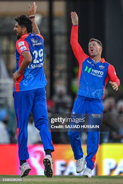 Delhi Capitals' Ishant Sharma celebrates with his teammate David Warner after taking the wicket of Punjab Kings' captain Shikhar Dhawan during the...