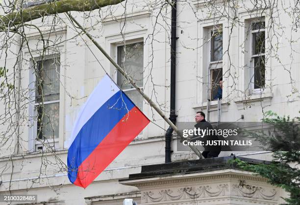 Person adjusts the national flag of Russia, flying at half-mast, outside the Russian embassy in London on March 23 a day after a gun attack in...
