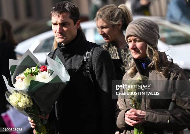 People arrive to lay flowers outside the Russian embassy in London on March 23 a day after a gun attack in Krasnogorsk, outside Moscow. Camouflaged...