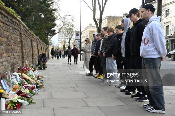 People pay their respects after laying flowers outside the Russian embassy in London on March 23 a day after a gun attack in Krasnogorsk, outside...