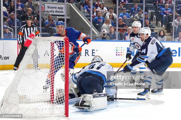 Kyle Palmieri of the New York Islanders scores a goal past Connor Hellebuyck of the Winnipeg Jets during the first period at UBS Arena on March 23,...