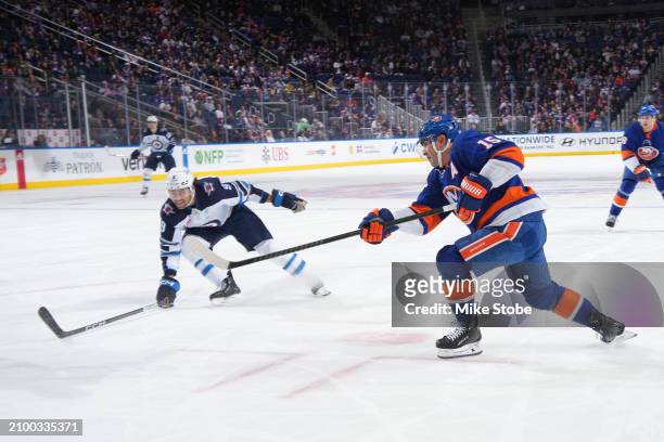 Cal Clutterbuck of the New York Islanders scores his second goal of the game as Alex Iafallo of the Winnipeg Jets defends during the first period at...